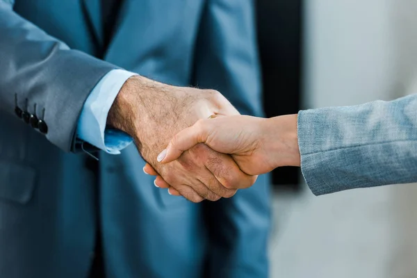 Cropped view of businessman and businesswoman shaking hands — Stock Photo