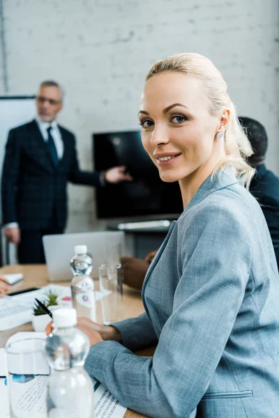 Foyer sélectif de femme d'affaires blonde heureuse près de coach d'affaires dans la salle de conférence — Photo de stock