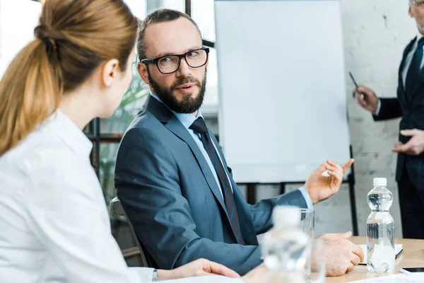 Messa a fuoco selettiva di uomo barbuto parlare con donna vicino business coach in sala conferenze — Foto stock