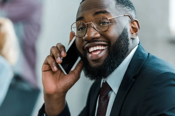 Barbudo y feliz afroamericano hombre hablando en el teléfono inteligente - foto de stock