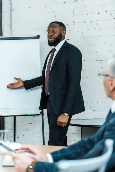 Вибірковий фокус красивого афроамериканського бізнес-тренера, який говорить і жестикулює біля білої дошки — стокове фото