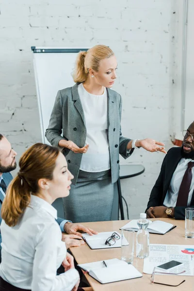 Focalizzazione selettiva del business coach incinta gesticolando mentre parla con l'uomo africano americano — Foto stock