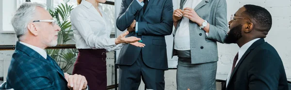 Panoramic shot of pregnant businesswoman standing near multicultural coworkers — Stock Photo