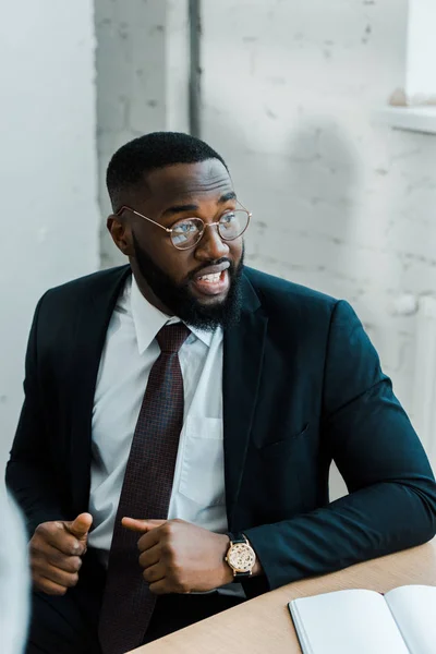 African american man in eye glasses sitting on conference room — Stock Photo