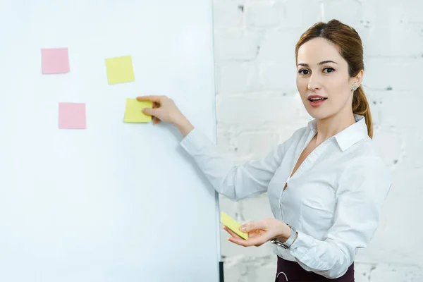 Treinador de negócios atraente colocando notas pegajosas no quadro branco — Fotografia de Stock