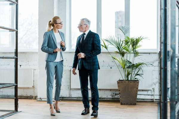 Attractive blonde businesswoman standing and talking with bearded businessman — Stock Photo