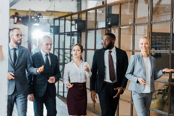 Groupe multiculturel de beaux hommes d'affaires et de femmes d'affaires heureuses marchant dans le bureau — Photo de stock