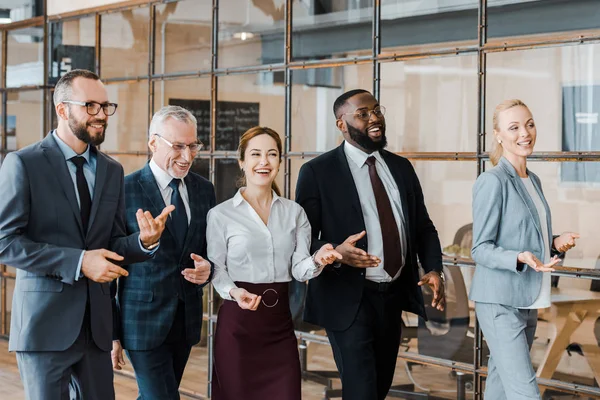 Groupe multiculturel d'hommes d'affaires joyeux et de femmes d'affaires heureuses marchant dans le bureau — Photo de stock