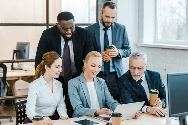 Joyeux hommes d'affaires multiculturels et femmes d'affaires regardant ordinateur portable — Photo de stock