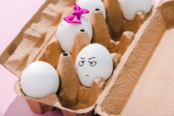 Egg with angry face expression in egg carton on pink — Stock Photo