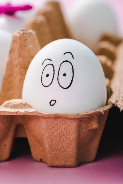 Enfoque selectivo de huevo con expresión de cara sorprendida en cartón de huevo - foto de stock