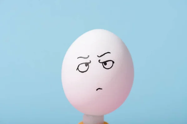 Huevo con expresión de cara enojada aislado en azul - foto de stock