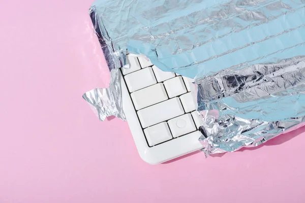 Top view of computer keyboard wrapped in silver foil on pink, Chocolate Bar concept — Stock Photo