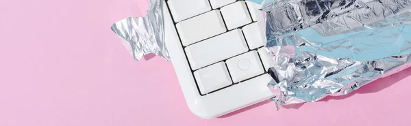 Colpo panoramico di tastiera del computer avvolto in lamina d'argento su rosa, concetto Chocolate Bar — Foto stock