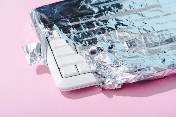 Teclado do computador envolto em folha de prata em rosa, conceito Chocolate Bar — Fotografia de Stock