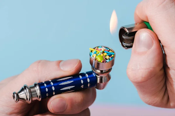 Vista ritagliata di illuminazione uomo Smoking Pipe con spruzzi colorati su blu, concetto di dipendenza da zucchero — Foto stock