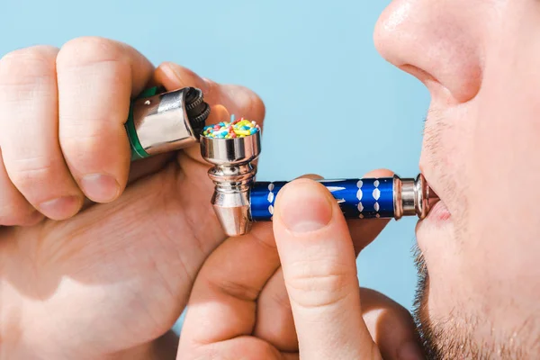 Vue recadrée de l'éclairage de l'homme Smoking Pipe avec des arrosages colorés isolés sur le bleu, concept de dépendance au sucre — Photo de stock