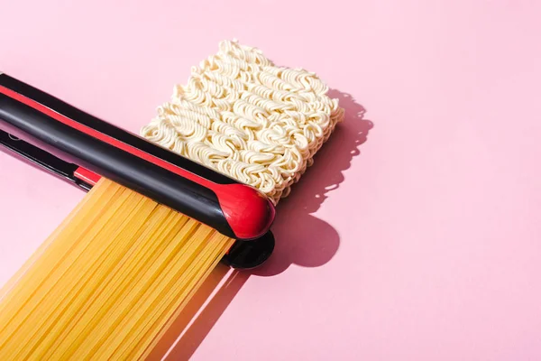 Plancha, espaguetis y fideos ondulados instantáneos en rosa, concepto de alisado del cabello - foto de stock