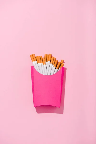 Vista superior de cigarrillos envasados en caja de papel en rosa con espacio para copiar, concepto de papas fritas - foto de stock