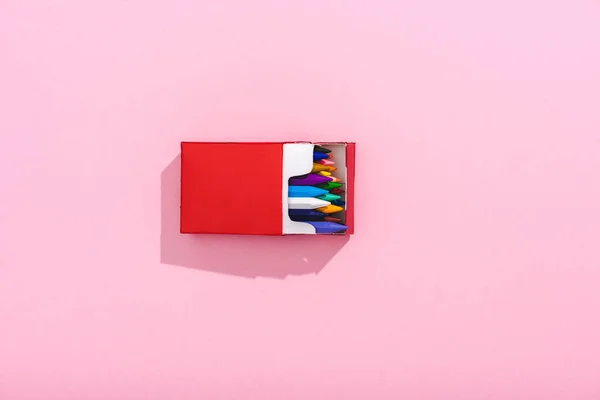 Top view of multicolored crayons in red cigarette pack on pink with copy space, smoking concept — Stock Photo