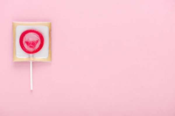Верхний вид презерватива, обернутый в леденец, изолированный на розовый с копировальным пространством, концепция безопасного секса — стоковое фото