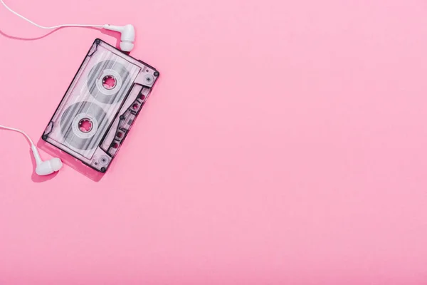 Vue du haut de la cassette audio vintage avec écouteurs sur rose avec espace de copie — Photo de stock