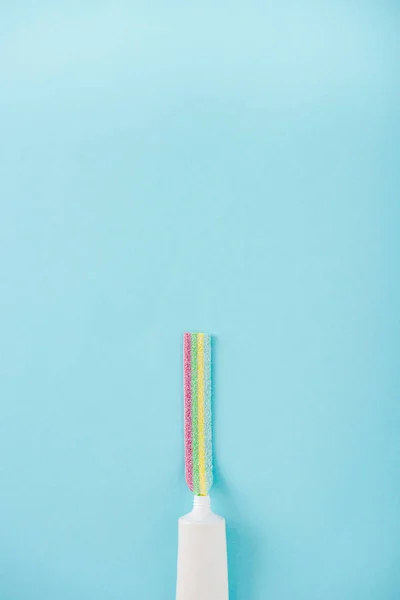 Top view of toothpaste tube with chewing colorful candy isolated on blue with copy space — Stock Photo