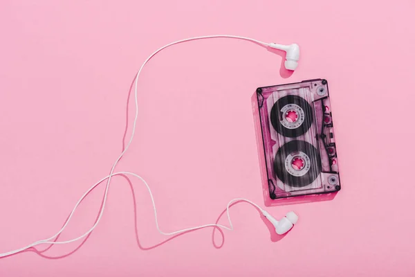 Top view of vintage audio cassette with earphones on pink, music concept — Stock Photo