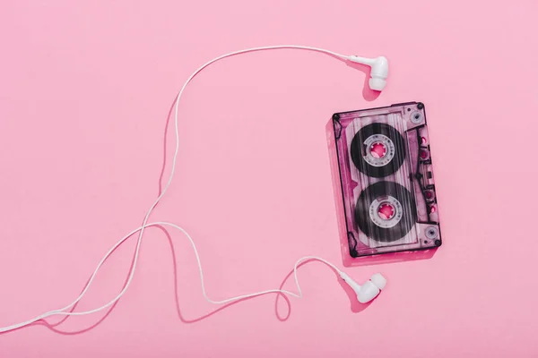 Vista superior de cassete de áudio vintage com fones de ouvido em rosa, conceito de música — Fotografia de Stock