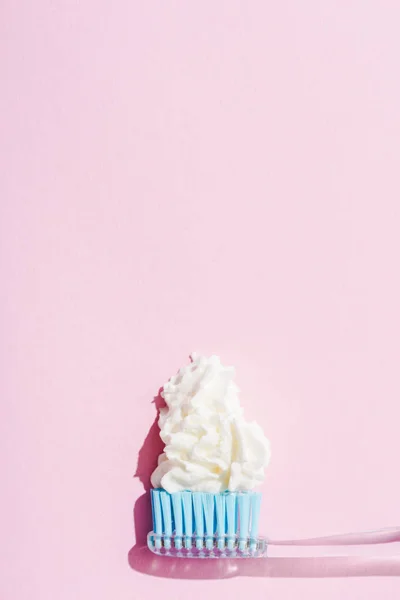 Vue du dessus de la brosse à dents avec dentifrice en crème fouettée sur rose avec espace de copie — Photo de stock