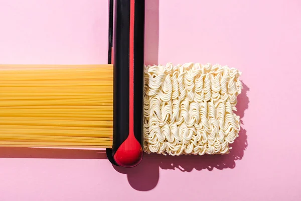 Top view of flat iron, spaghetti and wavy instant noodles on pink, hair straightening concept — Stock Photo