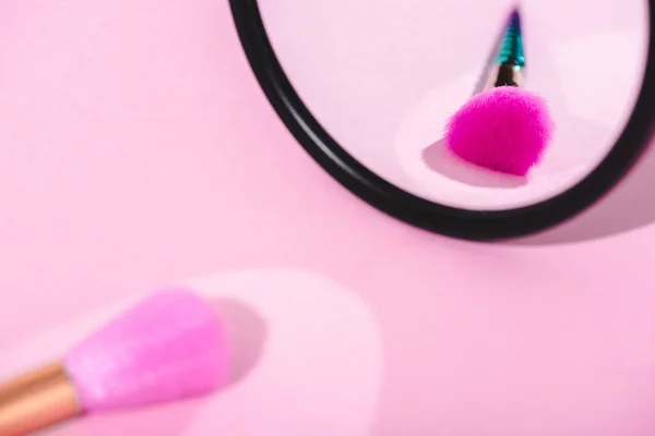 Cepillo de maquillaje con reflejo en espejo sobre rosa - foto de stock