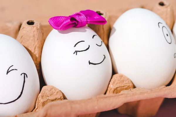 Vista de cerca de los huevos con diferentes expresiones faciales en cartón de huevo - foto de stock