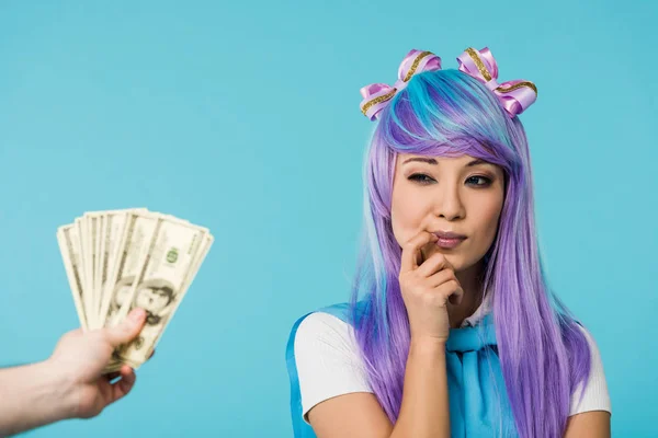 Recortado vista de hombre celebración dólar billetes y pensativo asiático anime chica aislado en azul - foto de stock
