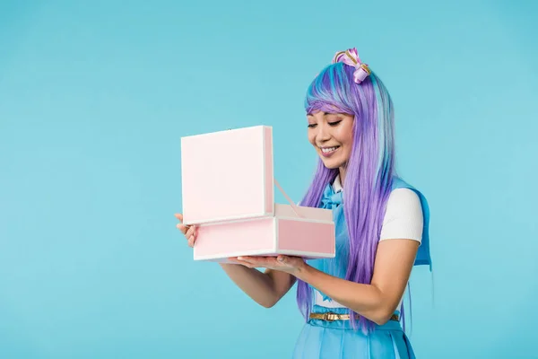 Sorridente asiatico anime ragazza holding aperto valigetta isolato su blu — Foto stock