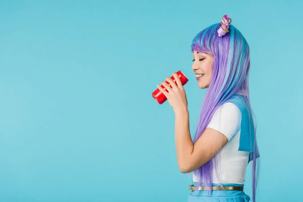 Вид збоку аніме дівчина п'є напій ізольовано на синьому — стокове фото