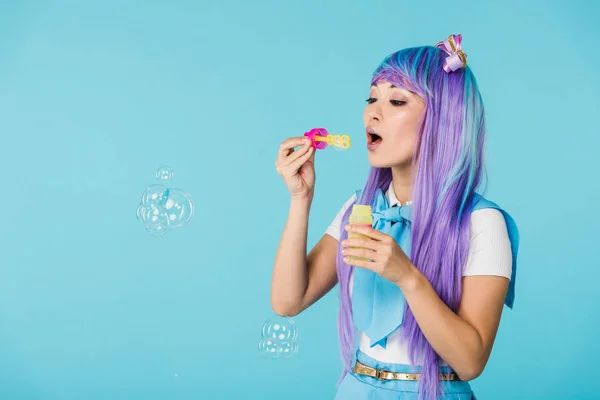 Ásia anime menina no roxo peruca com sabão bolhas isolado no azul — Fotografia de Stock