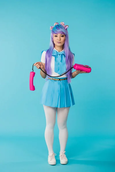 Largura completa vista de asiático anime chica con teléfono en azul - foto de stock