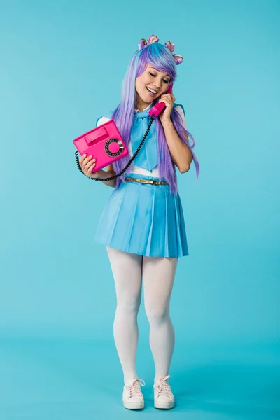 Full length view of asian anime girl talking on telephone on blue — Fotografia de Stock