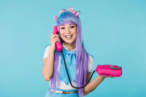 Sonriente asiático anime chica hablando por teléfono aislado en azul - foto de stock