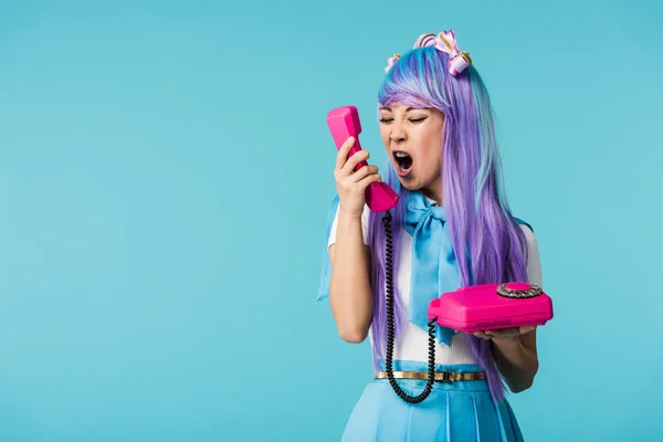 Angry asian anime girl screaming in handset isolated on blue — Stock Photo