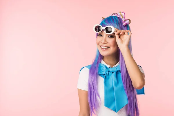 Chica de anime sonriente en peluca y gafas de sol aisladas en rosa - foto de stock