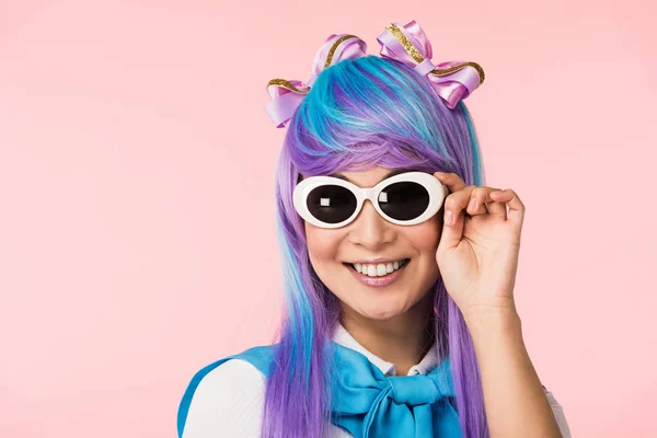 Smiling anime girl in wig and sunglasses isolated on pink — Stock Photo