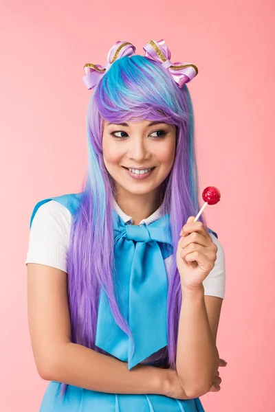 Dreamy asian anime girl in wig holding lollipop isolated on pink — Stock Photo