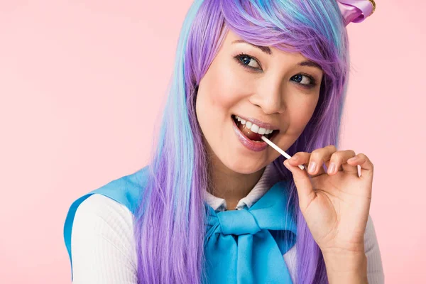 Happy asian otaku girl in wig eating lollipop isolated on pink — Stock Photo