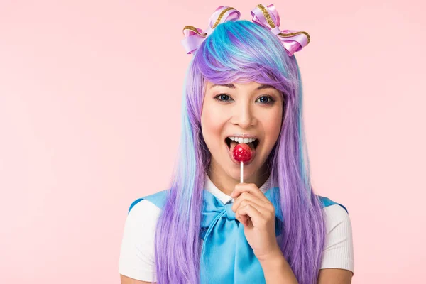 Feliz ásia otaku menina no peruca comer pirulito isolado no rosa — Fotografia de Stock