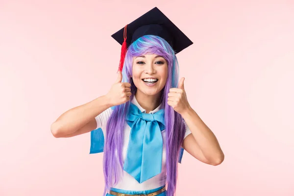 Vorderseite eines lachenden asiatischen Anime-Mädchens in akademischer Mütze, das vereinzelt die Daumen nach oben auf rosa zeigt — Stockfoto