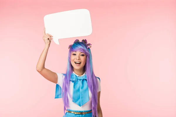 Excited asian anime girl in purple wig holding speech bubble on pink — Stock Photo