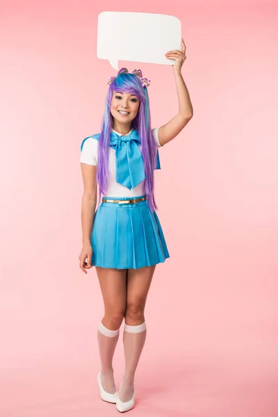 Full length view of excited asian anime girl in purple wig holding speech bubble on pink — Fotografia de Stock