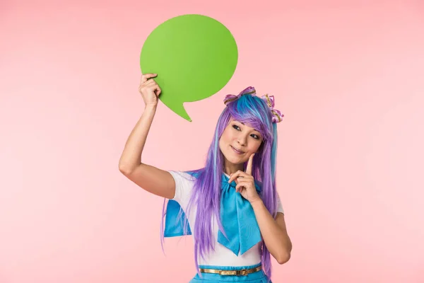 Asiático anime chica holding verde discurso burbuja y mostrando idea signo en rosa - foto de stock